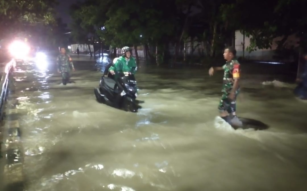 Babinsa Koramil 0830/06 Benowo Berjibaku Atur Kemacetan Lalu Lintas Saat Diguyur Hujan Lebat